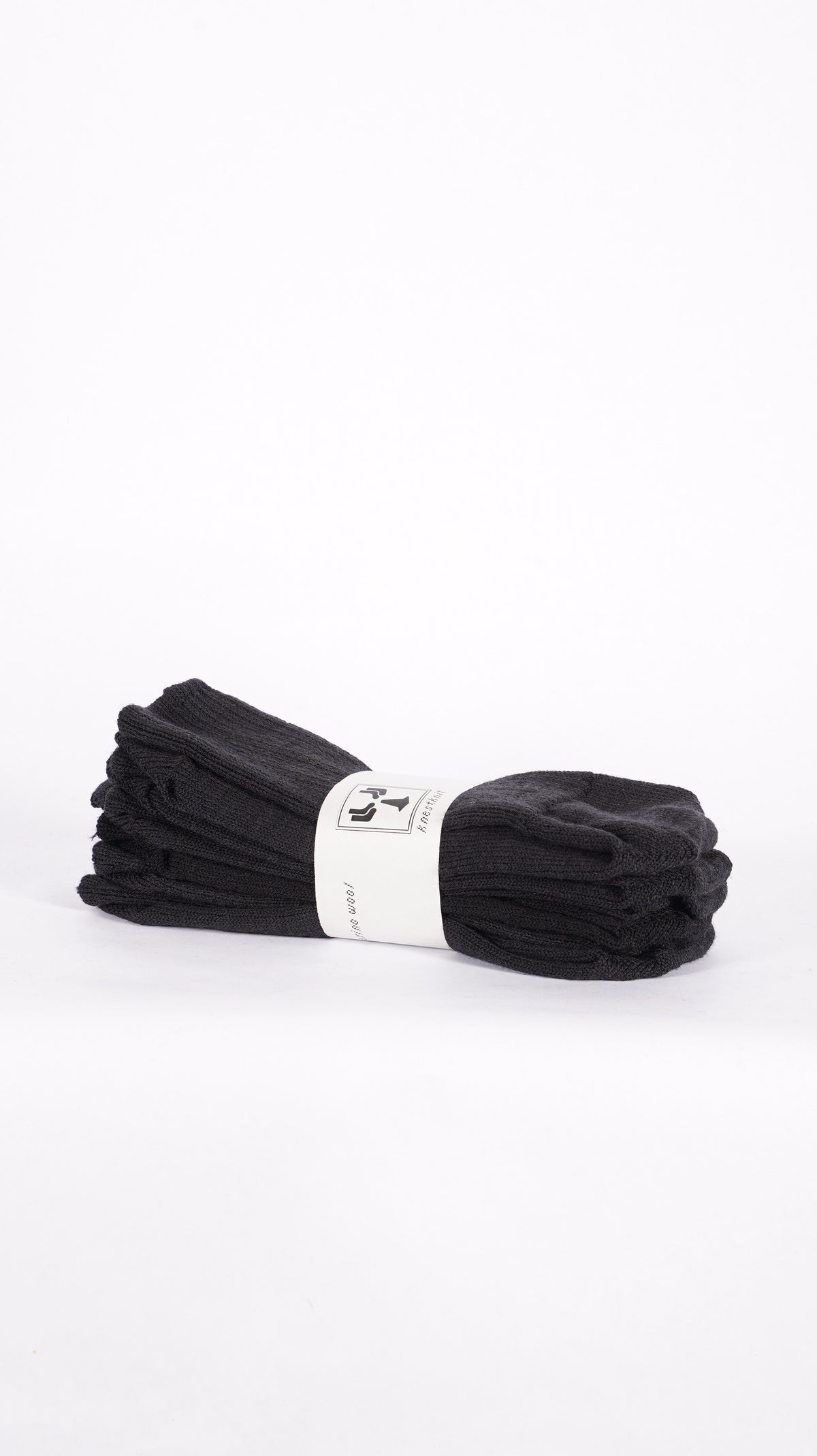 Pair of black KnestKnit merino rib socks folded together with a printed paper band.