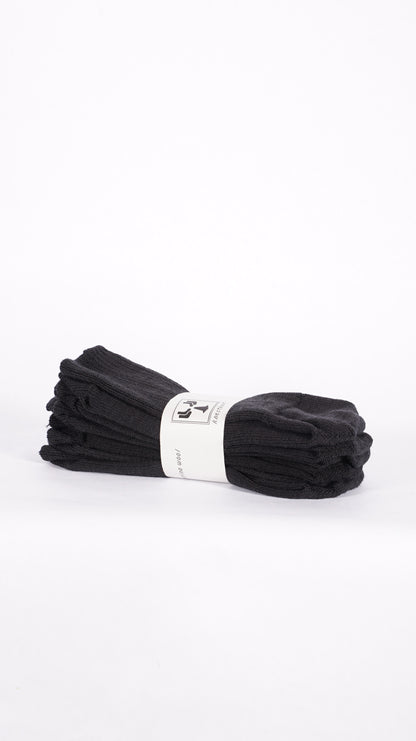 Pair of black KnestKnit merino rib socks folded together with a printed paper band.