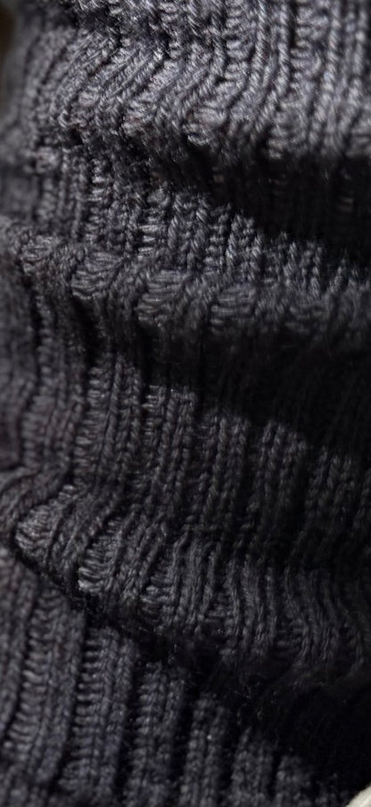 Close-up of the black merino sock's raised rib columns and knitted loops.